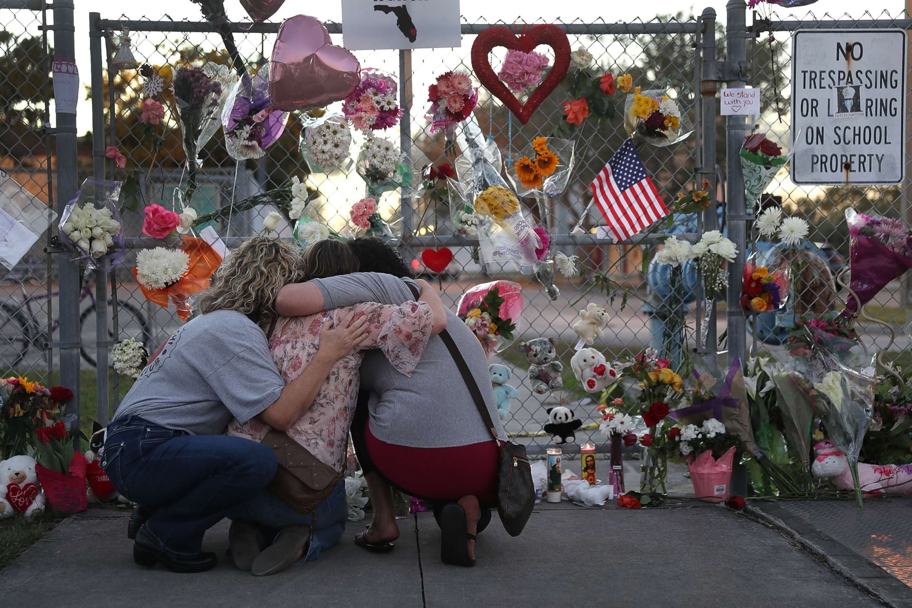 PHOTO: Shari Unger, Melissa Goldsmith and Giulianna Cerbono (L-R) hug each other as they visit a makeshift memorial setup in front of Marjory Stoneman Douglas High School on Feb. 18, 2018 in Parkland, Fl.